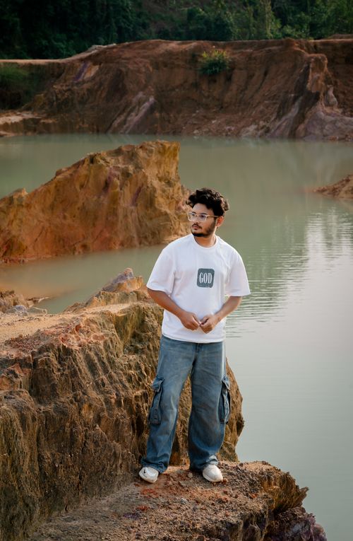 Free A man stands thoughtfully by a serene lake surrounded by rocky terrain in Bangladesh. Stock Photo