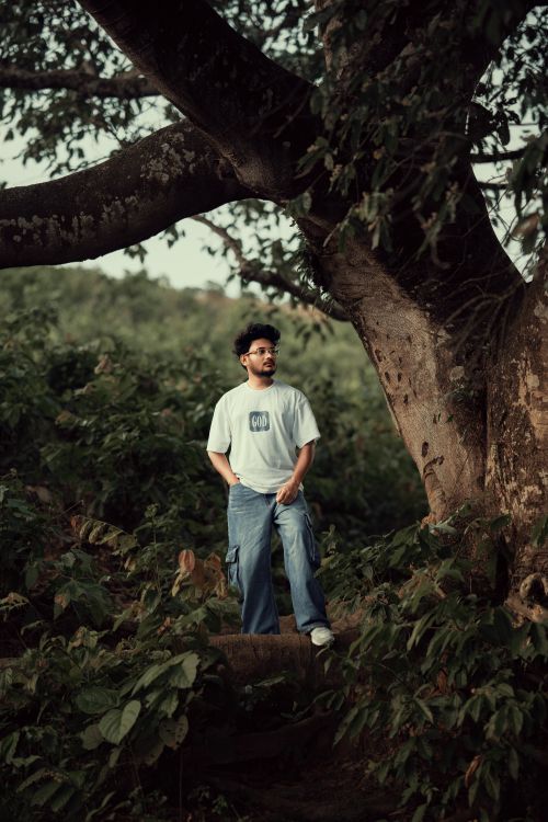 Free Portrait of a young man standing in a lush tropical forest in Bangladesh, embracing nature. Stock Photo