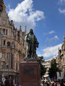 Bronze statue of Van Dyck in Antwerp, Belgium, under a bright blue sky.