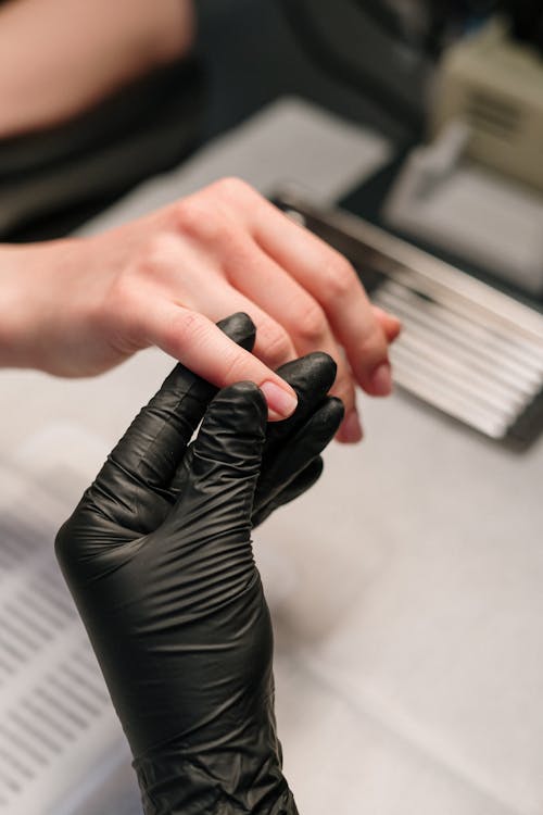 Person in Black Leather Gloves Holding Black and White Book