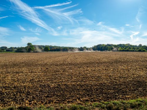 Free Expansive plowed field in Coesfeld, Germany, under a bright blue sky with wispy clouds. Stock Photo