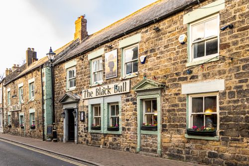 Free Historic stone facade of The Black Bull pub on a quiet street, capturing its rustic charm. Stock Photo