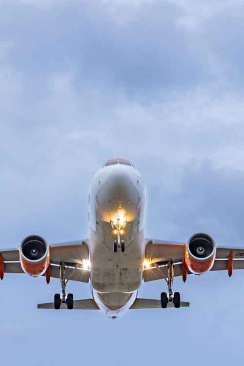 Free Front view of a commercial airplane flying through clouds during the day. Stock Photo