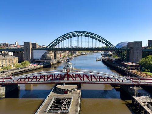 Free Scenic view of the iconic Tyne Bridge spanning the River Tyne in Newcastle, with clear blue skies. Stock Photo
