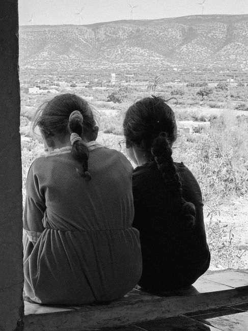 Fotomural Dos niñas pequeñas con el pelo trenzado están sentadas juntas contemplando un pintoresco paisaje montañoso.