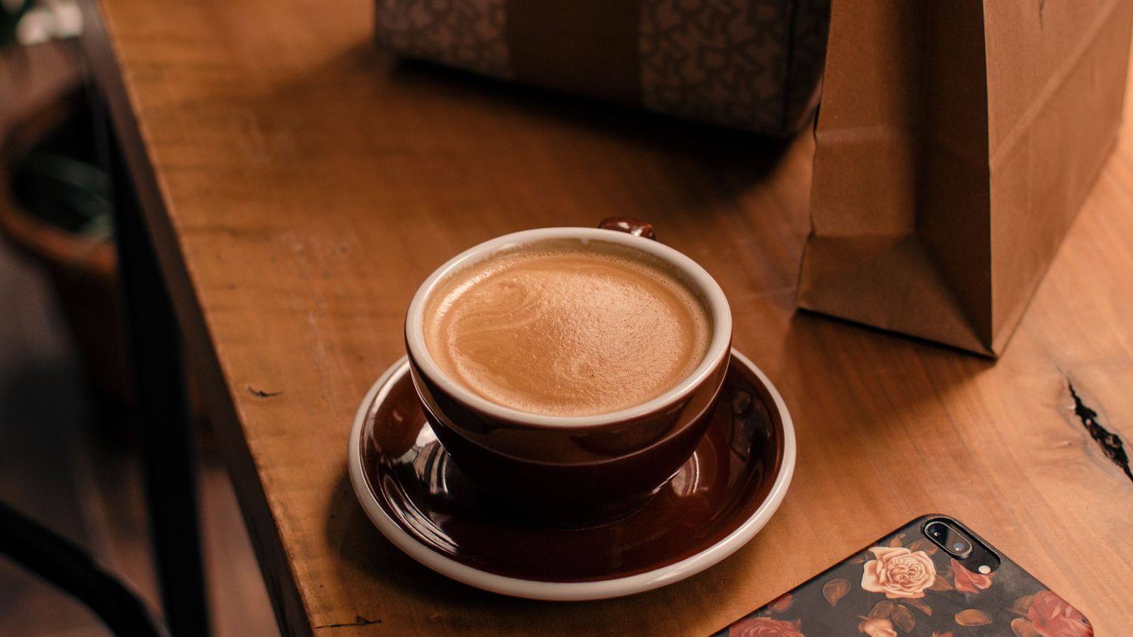 Coffee and a phone on a wooden café table