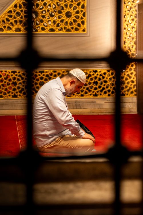 Free A man in traditional attire prays inside a beautifully decorated mosque in Istanbul. Stock Photo