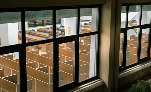 Free A solitary student studies in a library with individual study cubicles and wooden desks. Stock Photo