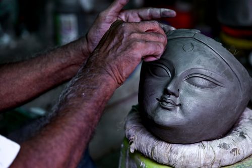 Free Close-up of an artisan crafting a clay Durga idol head in Kolkata, India, epitomizing traditional artistry. Stock Photo