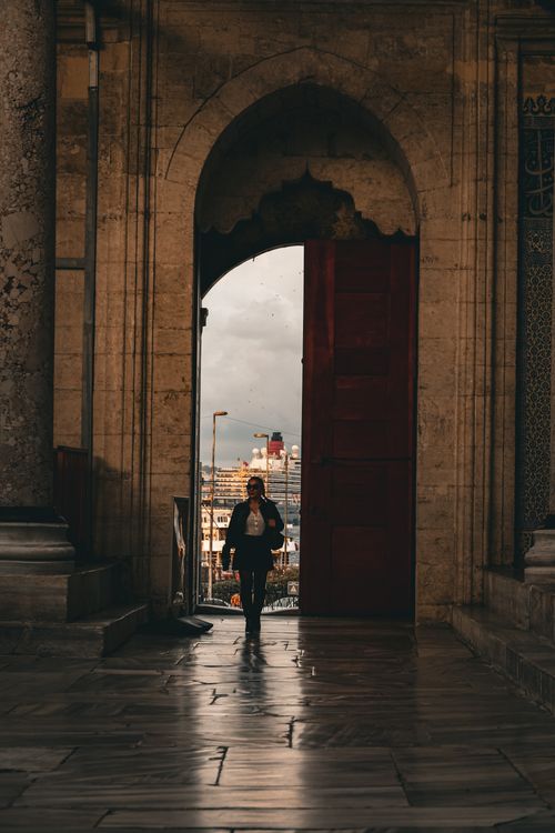 Free Person walking through archway in Istanbul with city view beyond. Moody lighting. Stock Photo