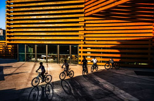 Free Group of cyclists in front of a modern building with striking wooden structure. Stock Photo