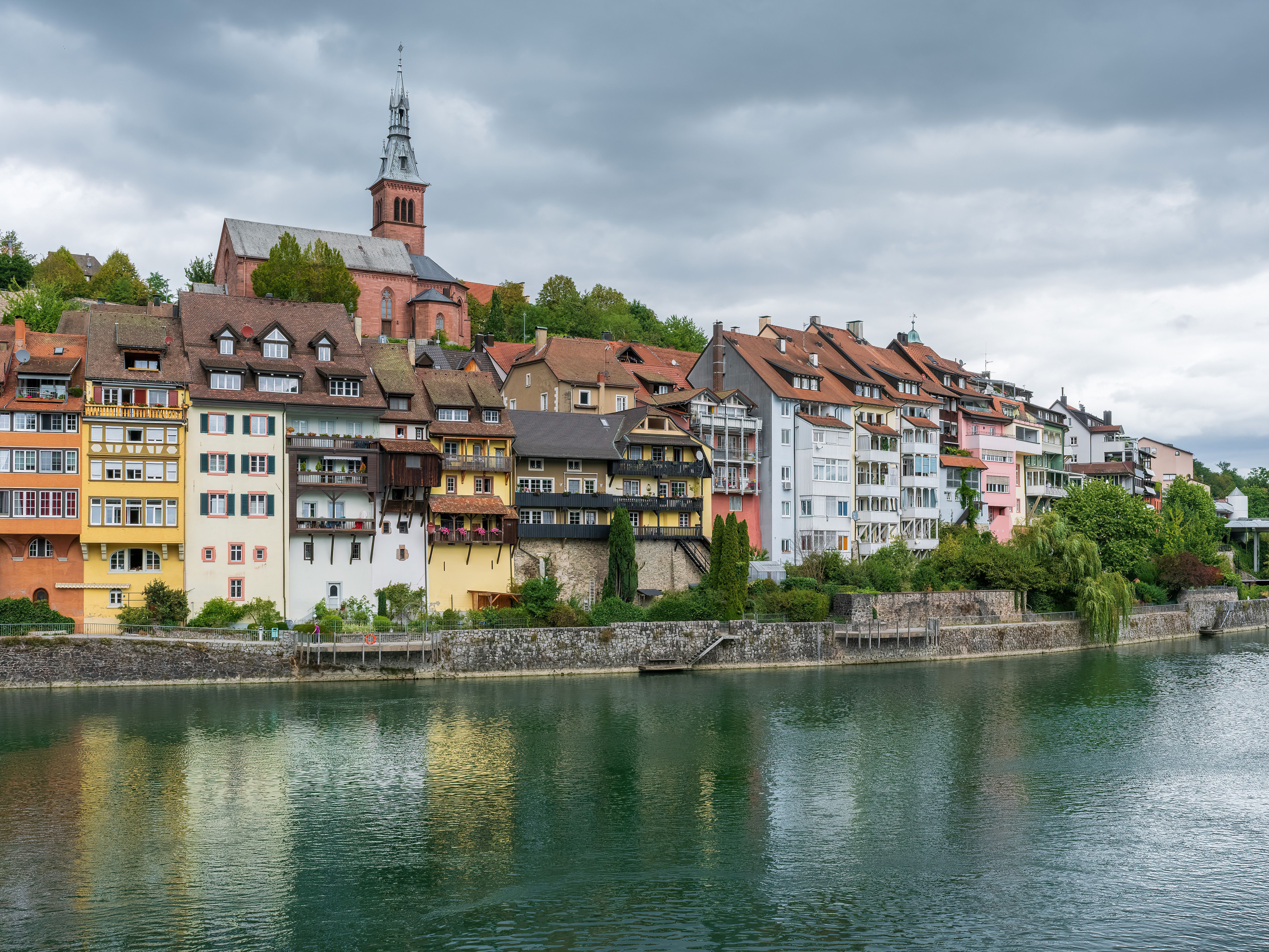 Picturesque view of colorful European buildings by a river under cloudy skies.