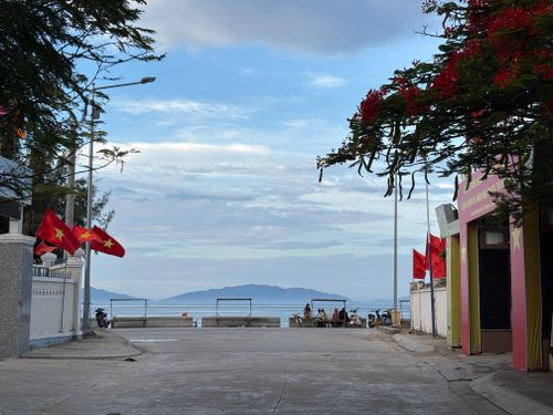 Free Peaceful seaside scene with red Vietnamese flags and distant islands in Vietnam. Stock Photo