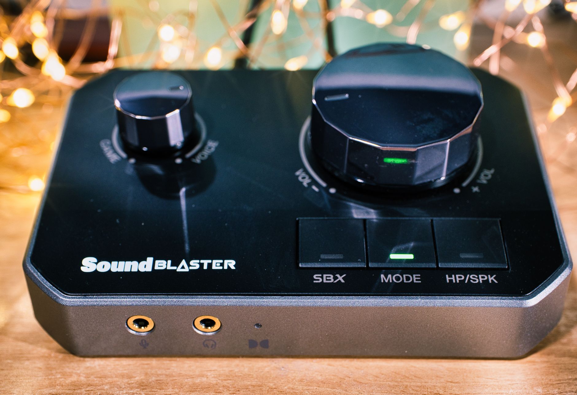 Close-up of a Creative SoundBlaster DAC with glowing lights on a wooden surface.