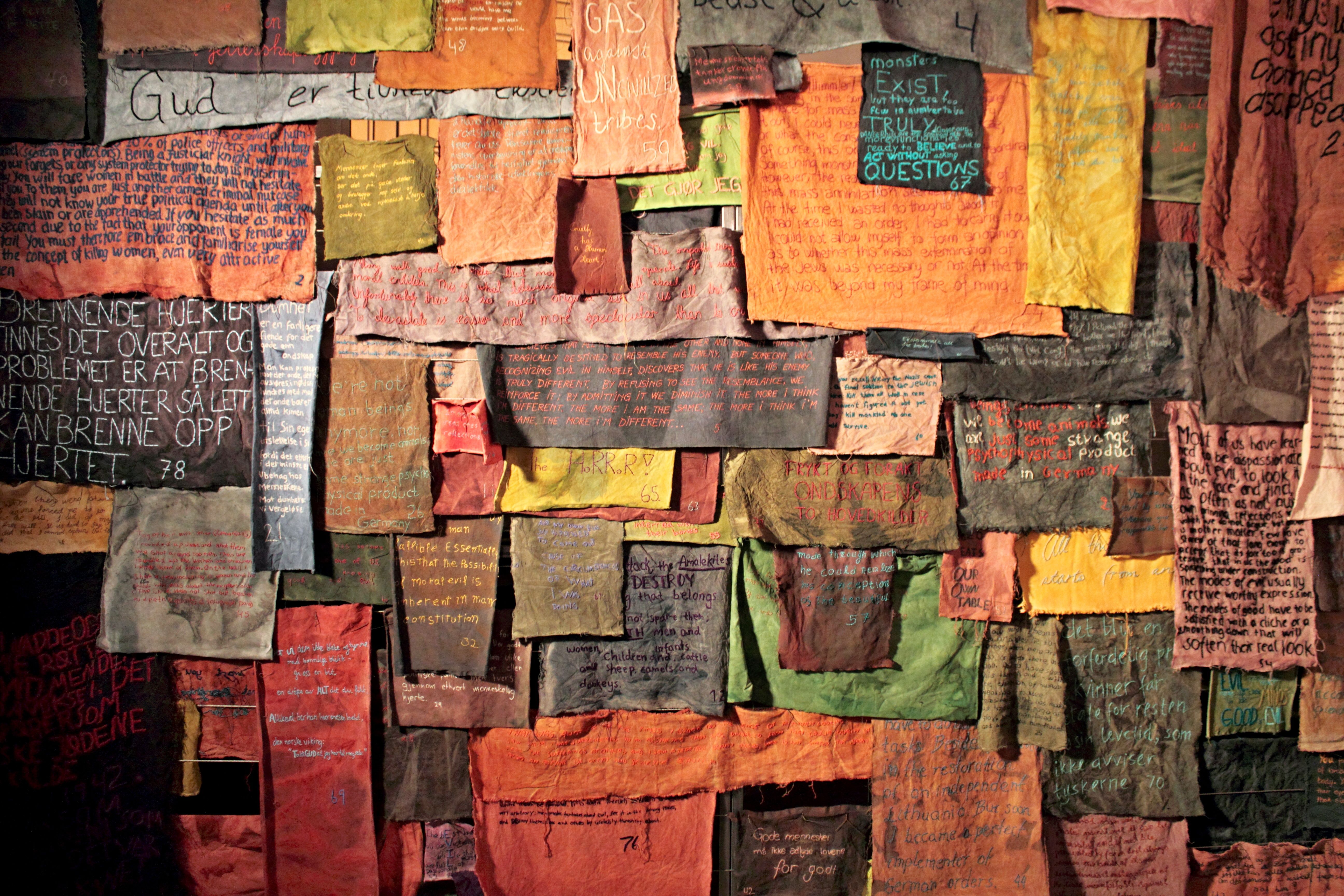 Vibrant cloth pieces with handwritten messages hung on a rustic wall, showcasing creativity.