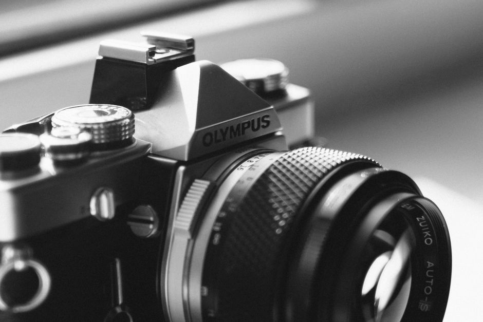 Close-up of a vintage Olympus camera lens in monochrome, showcasing intricate details.