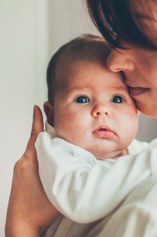 Free Tender close-up of a mother lovingly holding her baby indoors. Stock Photo