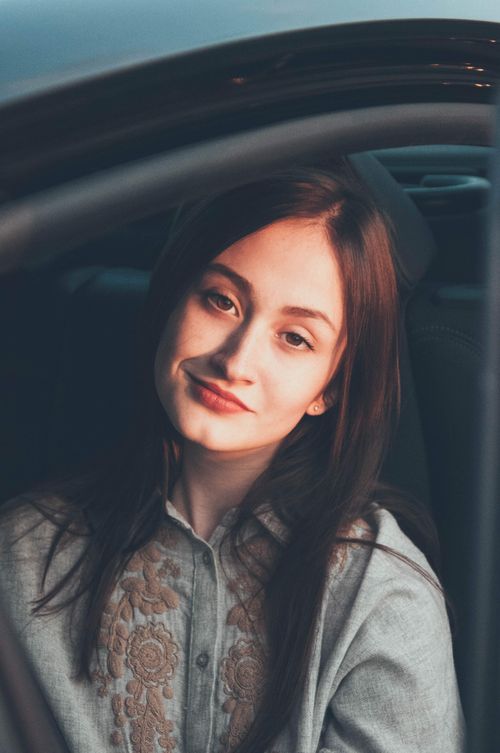 Free Portrait of a young woman with a gentle smile, photographed in a car seat. Stock Photo
