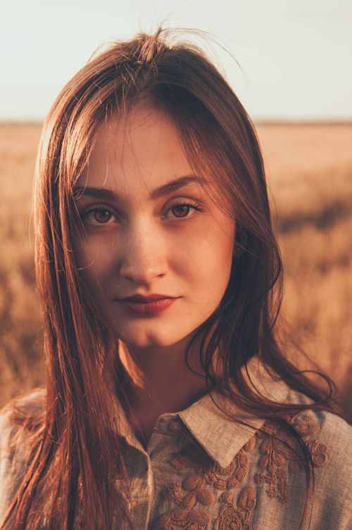 Free A young woman stands in a sunlit wheat field, capturing the essence of summer. Stock Photo