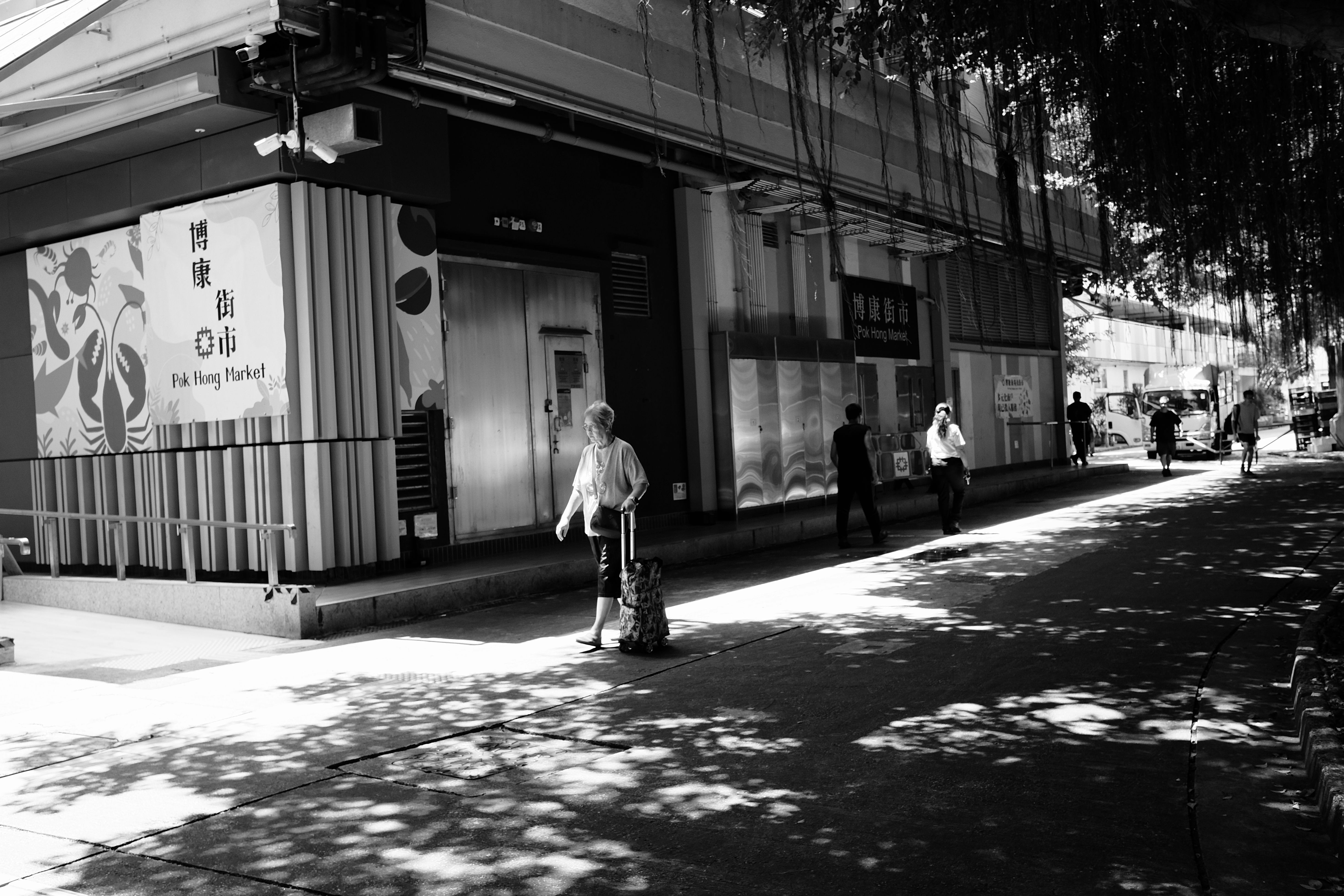 Street scene with people near Pok Hong Market in black and white, showcasing urban daily life.