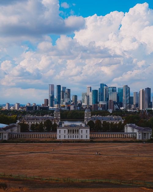 Free A panoramic view from Greenwich Park capturing London's iconic skyline with vibrant blue sky. Stock Photo