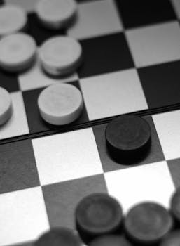 Close-up of a black and white checkers board with game pieces arranged in play.