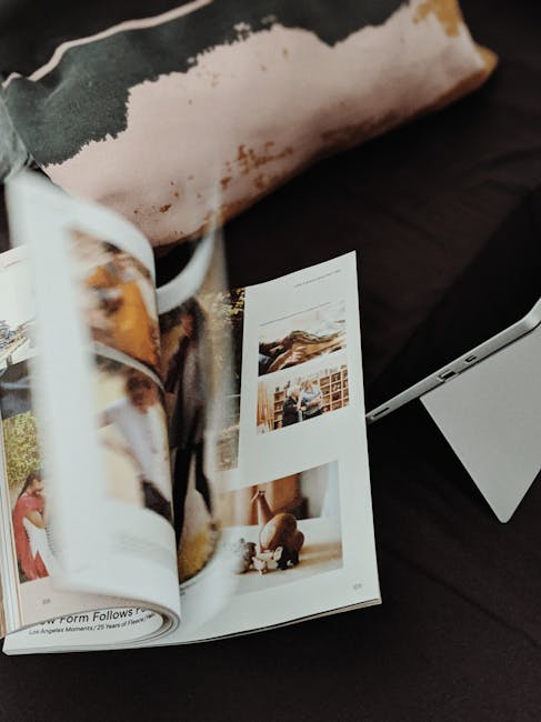 Close-up of an open magazine with blurred pages and a tablet on a dark surface.