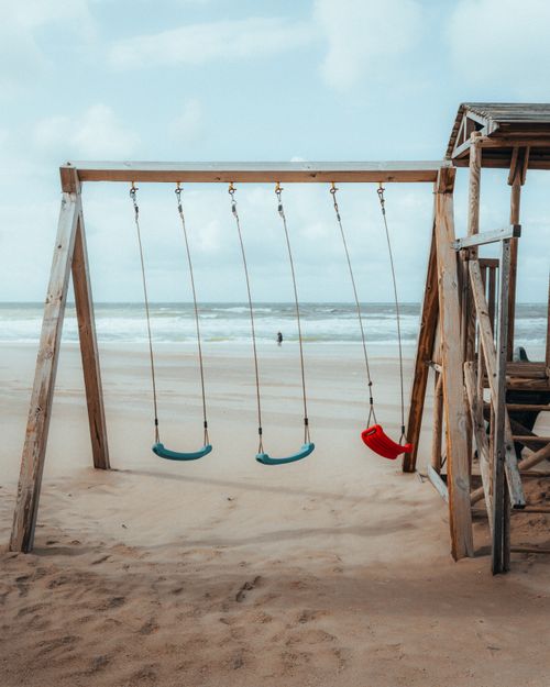 Free A tranquil beach scene with a wooden swing set facing the sea at The Hague, Netherlands. Stock Photo