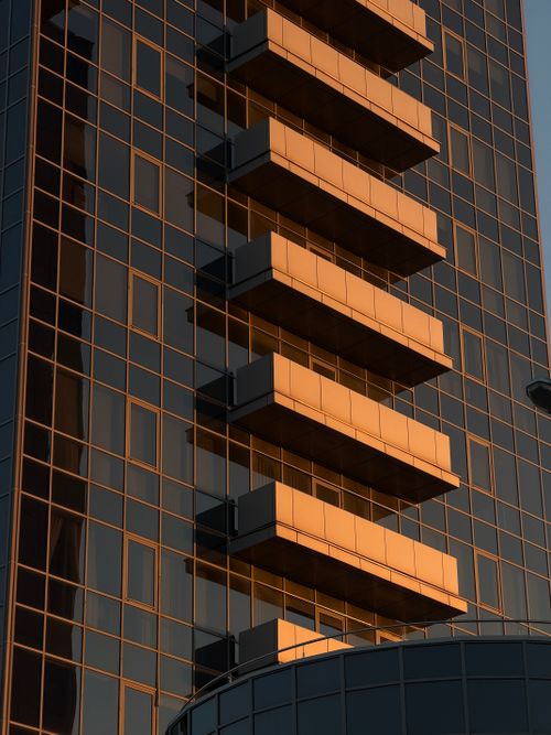 Free A sleek modern skyscraper with striking golden reflections from the sunset, showcasing architectural elegance. Stock Photo
