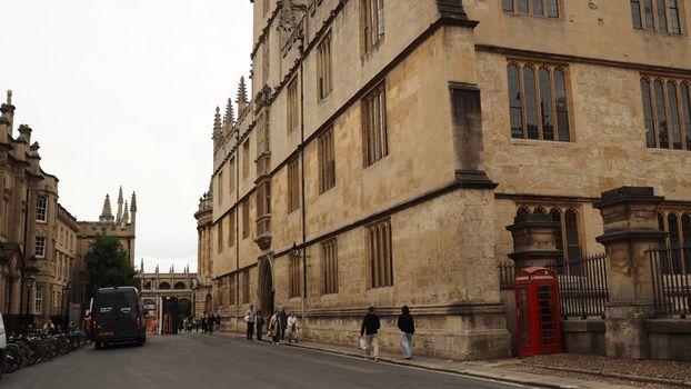View of a historic street in Oxford featuring grand architecture and a classic red telephone booth.