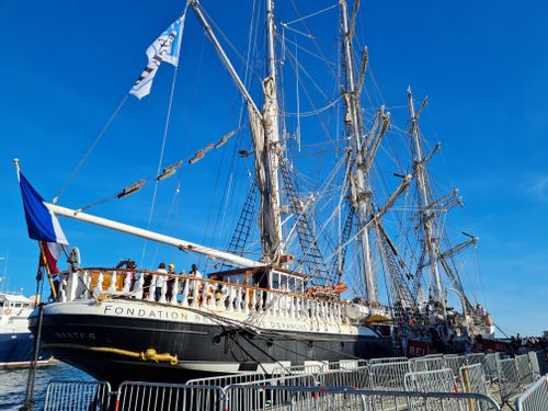 Free A stunning tall ship docked at Sète harbor, showcasing intricate rigging and a French flag. Stock Photo