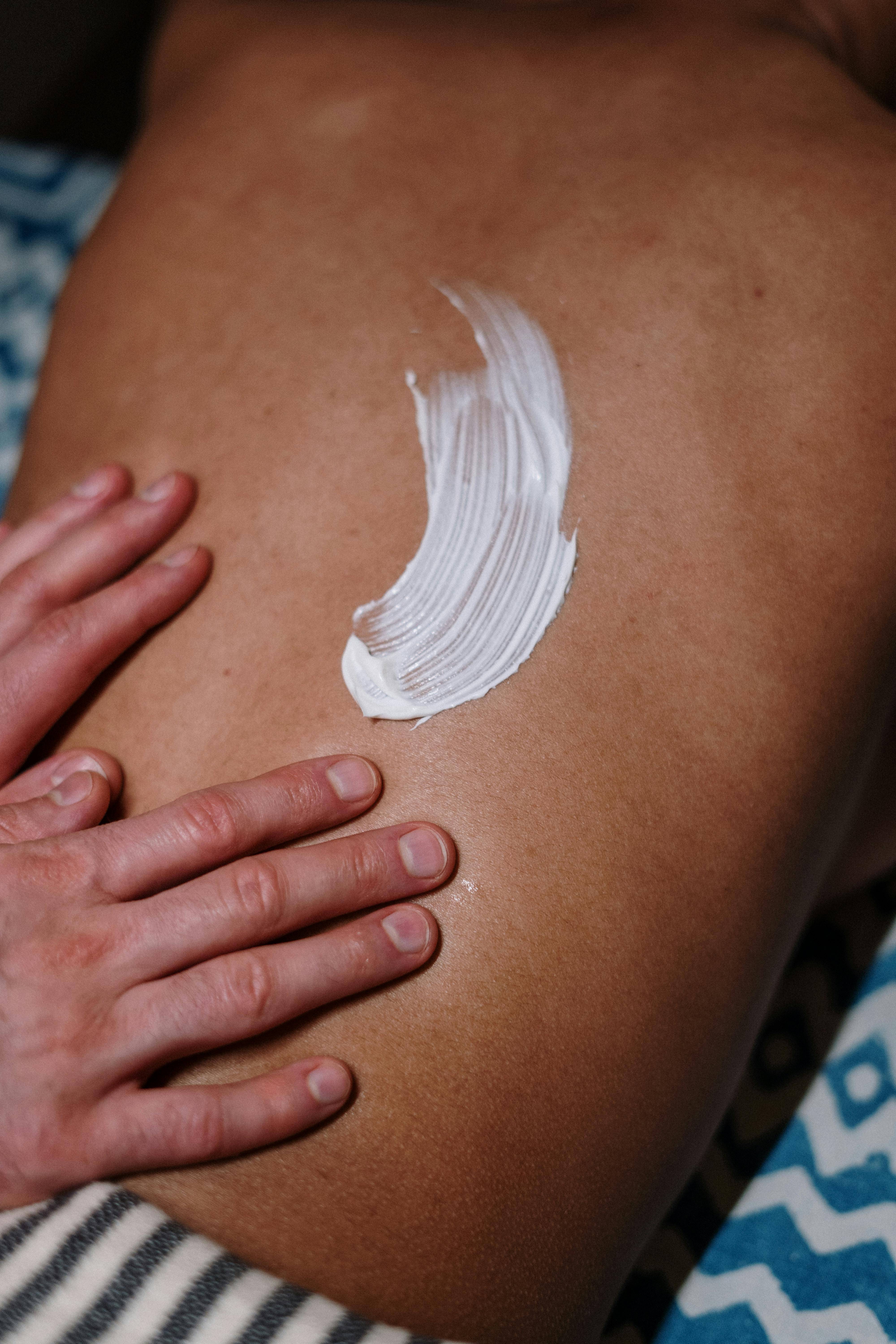 topless woman lying in bed having a back massage