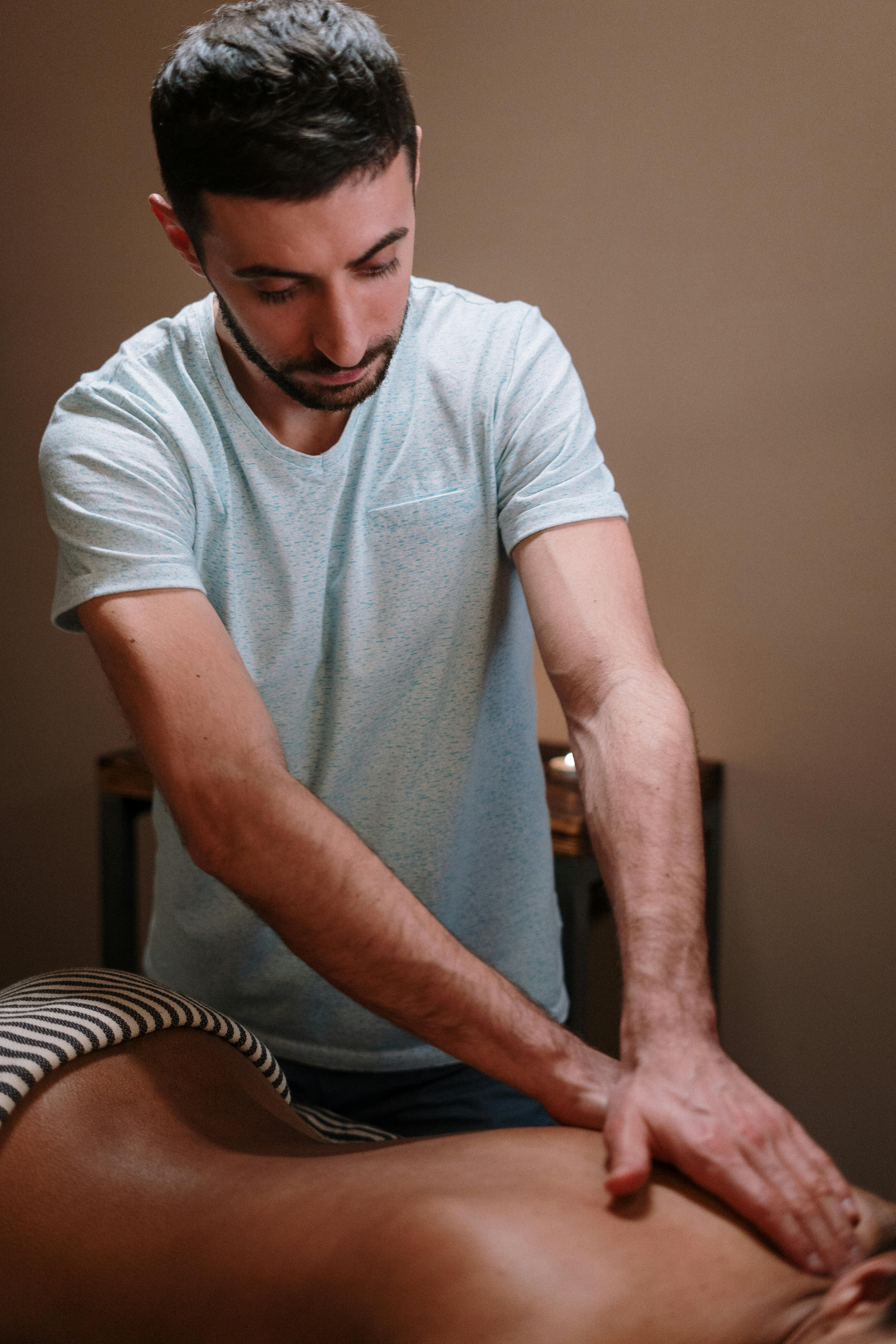 man in white crew neck t shirt and blue denim jeans sitting on chair