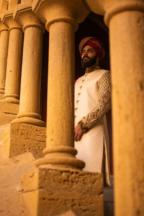 Indian Sikh man in turban standing behind ancient colonnade