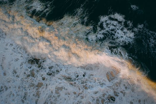 A breathtaking aerial shot capturing the motion and beauty of ocean waves crashing against the shore.