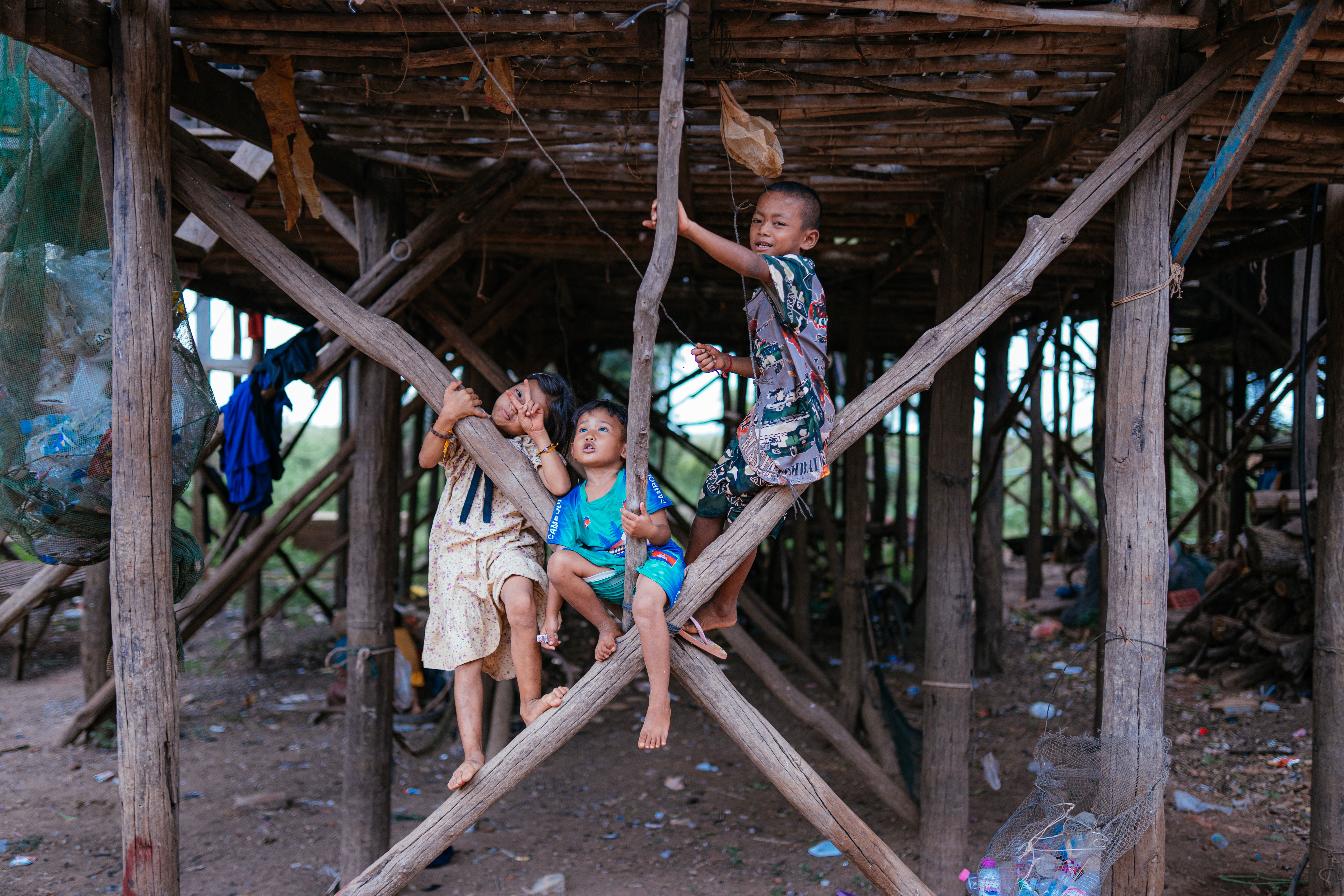 Children enjoy playful moments under a traditional stilt house in rural Cambodia.