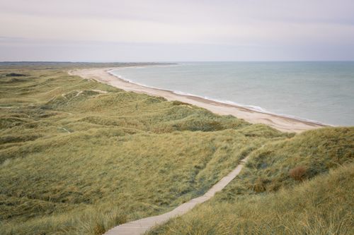 Free Vast rolling dunes meet the serene sea along the Fjerritslev coast in Denmark. Stock Photo
