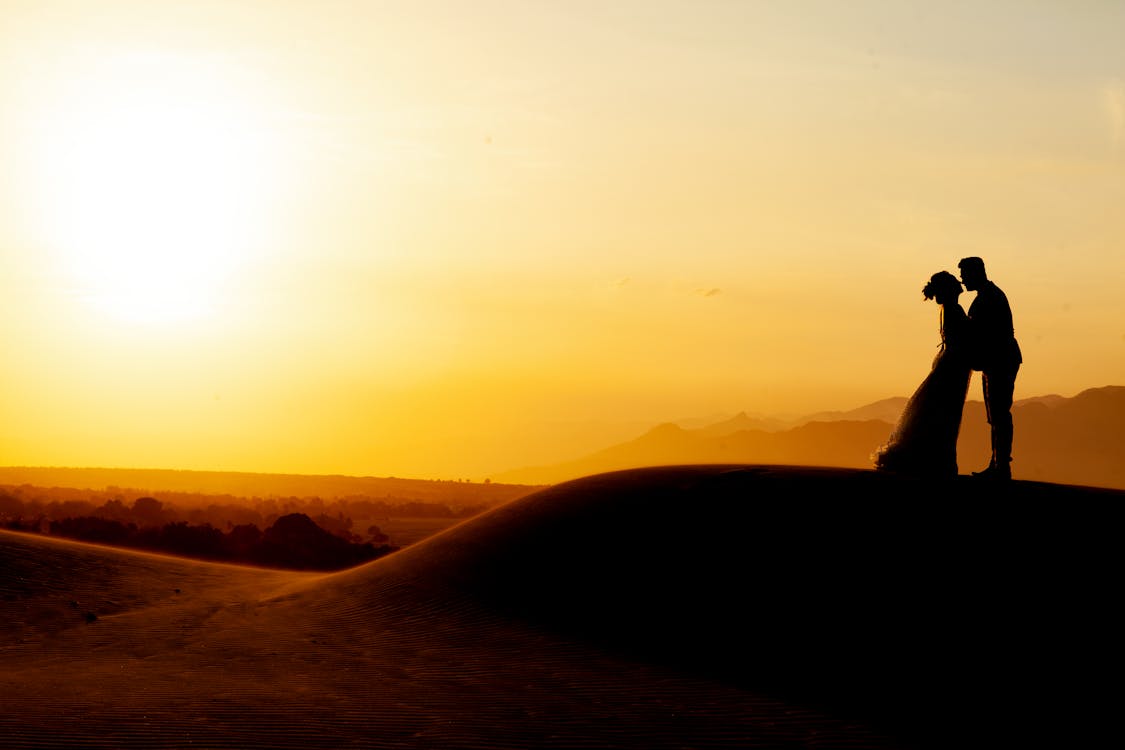  Silhouette of Man and Woman Standing on Rock Formation during Sunset 