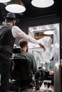 Man in Black Hat Cutting Hair of Man in Green Shirt