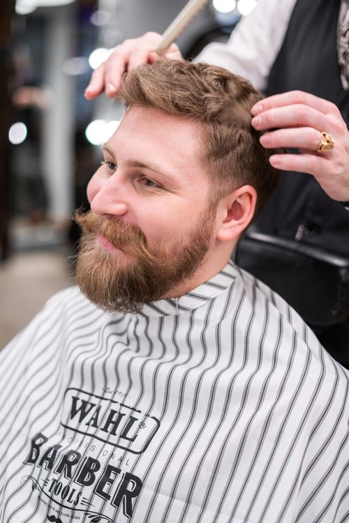 Free A stylish bearded man getting a haircut in a modern barbershop. Stock Photo