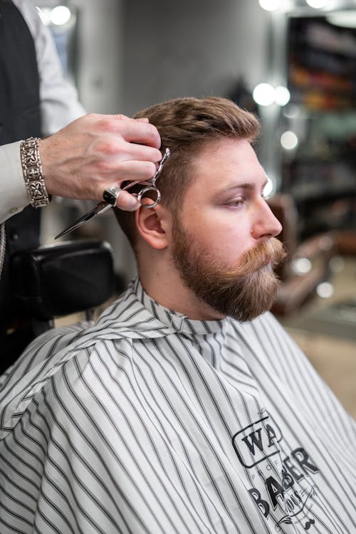 Barbero en el trabajo Vista lateral de joven hombre barbudo - foto de stock  3880143