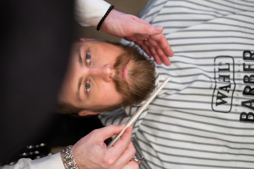 Free A bearded man receives grooming care at a professional barber shop. Stock Photo
