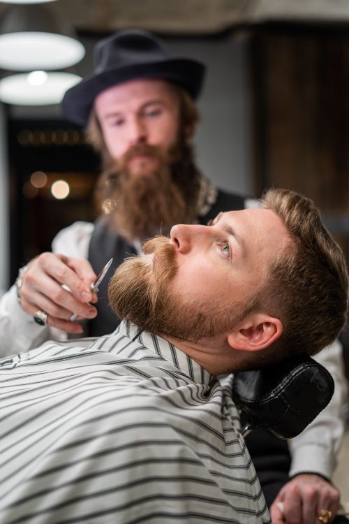Free Focused barber prepares to shave a bearded client in a stylish barbershop setting. Stock Photo