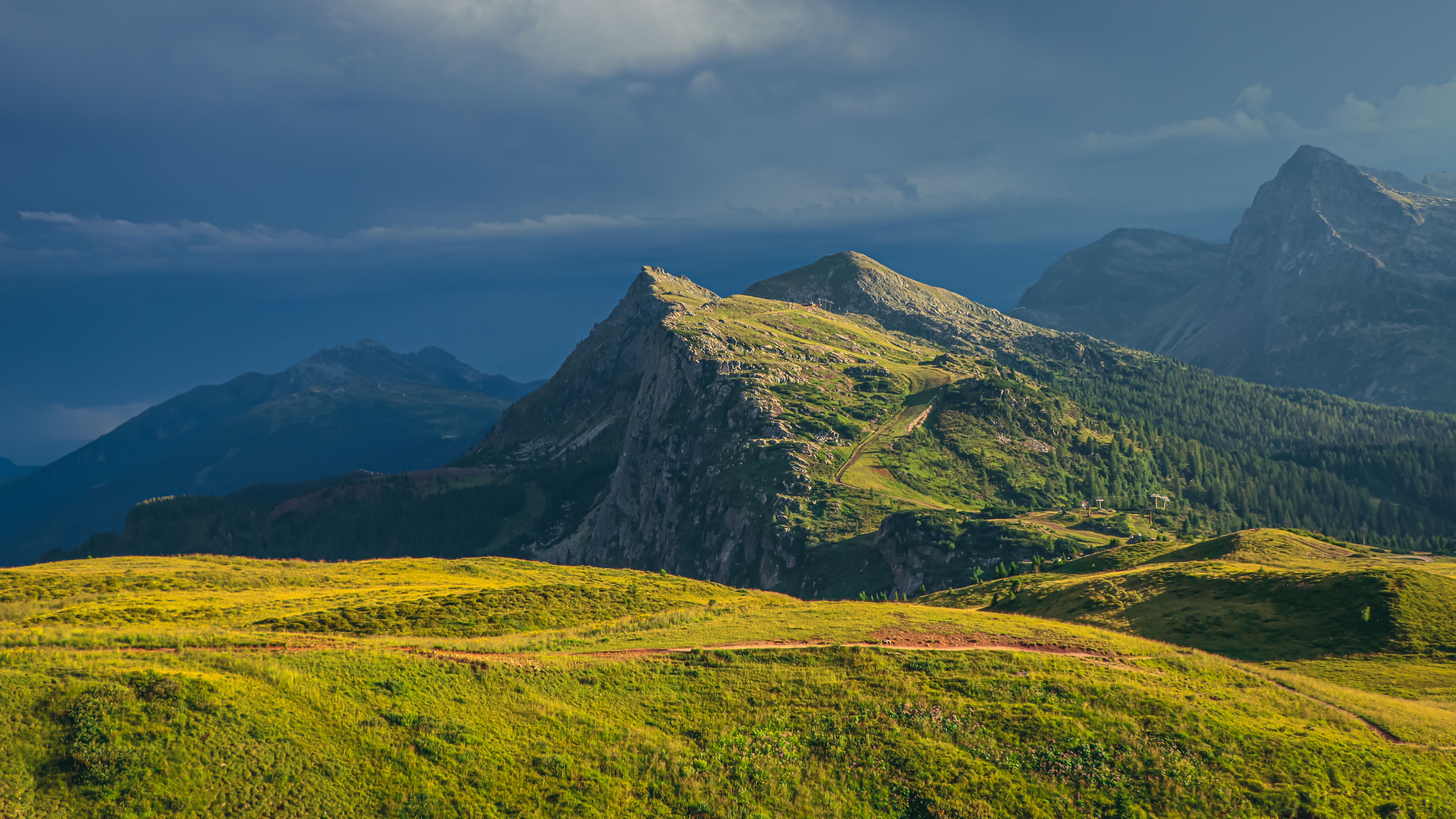 dramatic alpine mountain peaks and green hiking valley in sunlight