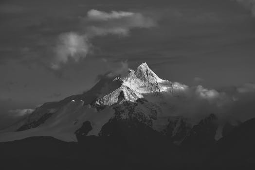 Stunning black and white image of a snow-capped mountain peak in Tibet, enveloped in clouds.
