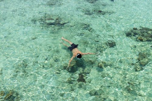 Free A person snorkels in crystal clear waters in Semporna, Sabah, Malaysia. Aerial view captures vibrant aquatic beauty. Stock Photo