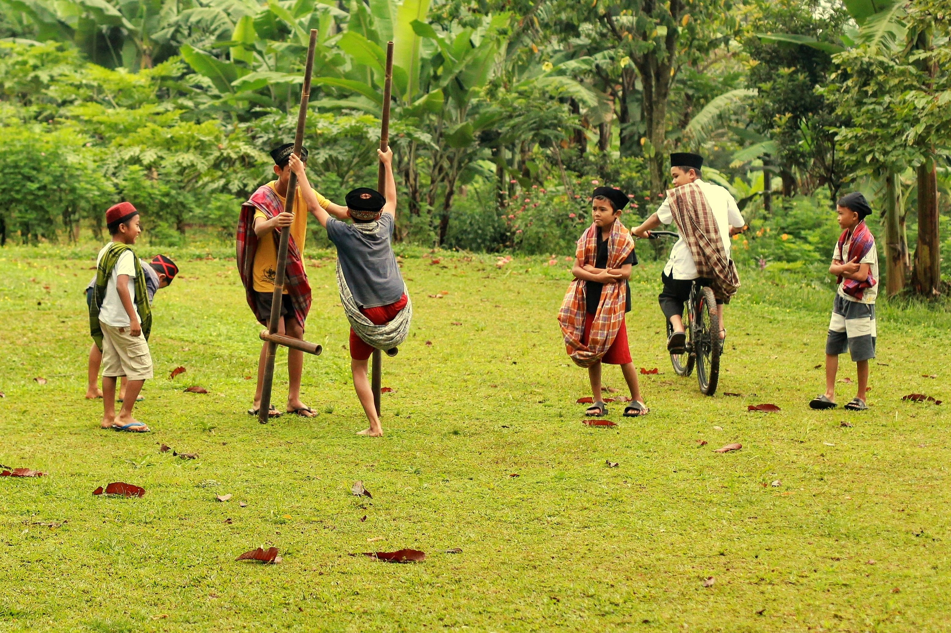 Boys enjoy traditional games in a lush field, capturing the essence of childhood in rural Indonesia.