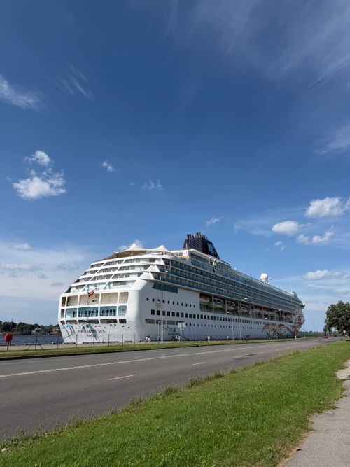 Free Majestic cruise ship docked by a coastal road under a vibrant blue sky, perfect for travel themes. Stock Photo