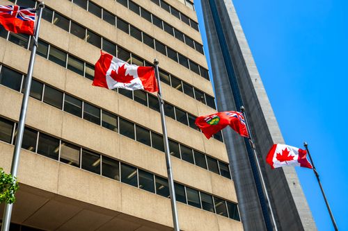 Free Flags of Canada and Ontario fluttering near the CN Tower under a clear blue sky in Toronto. Stock Photo