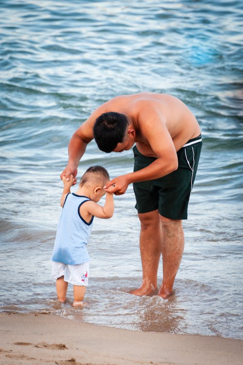 Free Man In Black Shorts Holding Baby At The Beach Stock Photo